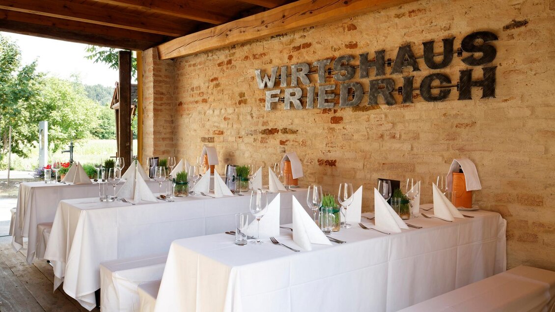 Ein einladender Speisesaal mit festlich gedeckten Tischen und einer rustikalen Backsteinwand. Der Raum strahlt eine warme, gemütliche Atmosphäre aus. | © Friedrich Andreas