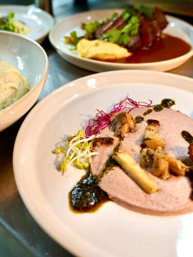 Various plates with meat, bread chips, mushroom cream, and dessert at the Schanzlwirt Graz restaurant. | © Wirtshaus Schanzlwirt