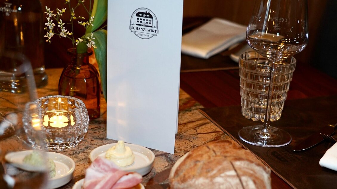 Gedeckter Tisch im Schanzlwirt Graz mit Brot, Aufstrichen, Speck, Weingläsern und Kerze | © Wirtshaus Schanzlwirt