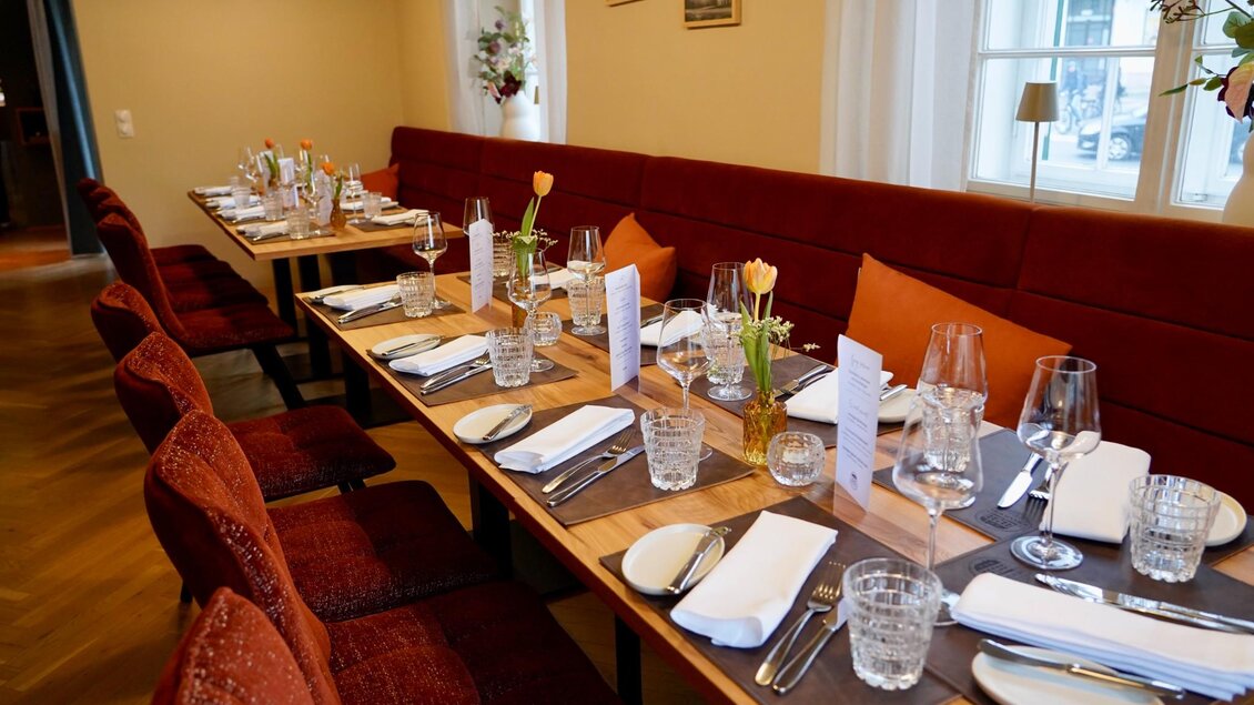 Lang gedeckter Tisch mit Gläsern, Menükarten und Blumen im modernen Speiseraum des Schanzlwirt Graz | © Wirtshaus Schanzlwirt