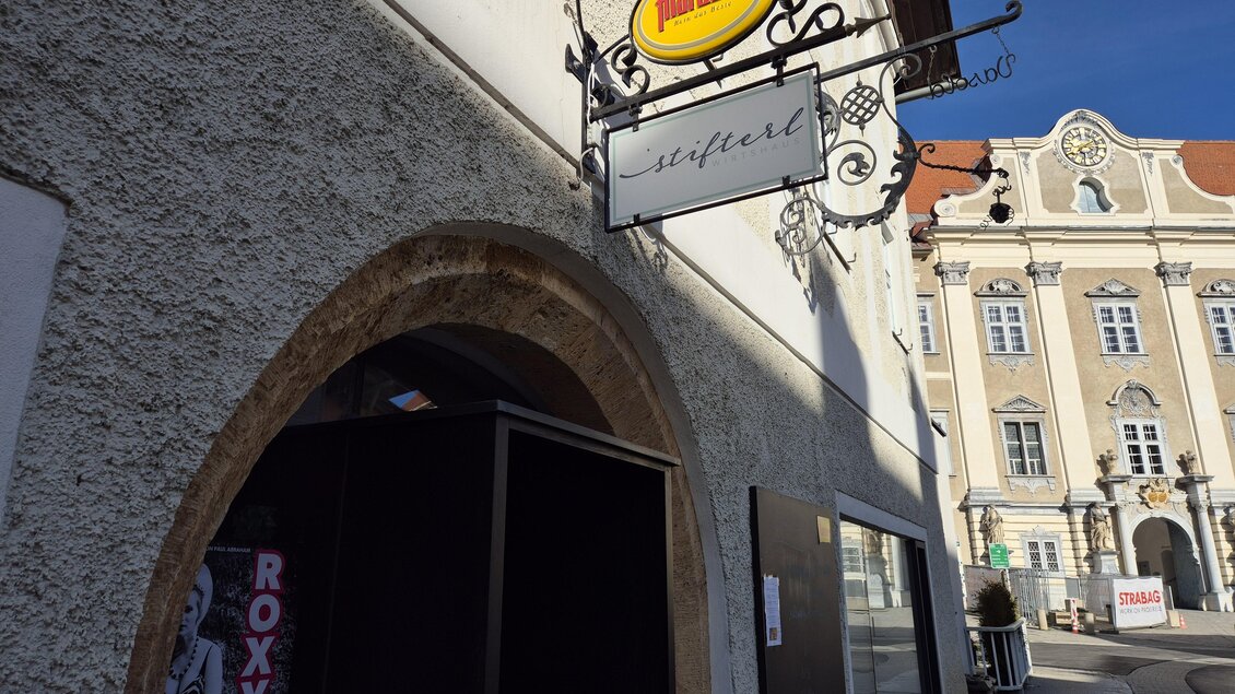 Ein einladender Eingangsbereich eines Geschäftes mit einem auffälligen Schild. Im Hintergrund sind historische Gebäude sichtbar. | © Tourismusverband Murau