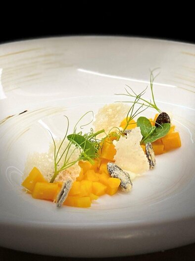 An artistically arranged plate with orange and green herbs. The dish combines fresh ingredients with an elegant design. | © Wirtshaus Thorbauer - Julian Wallner