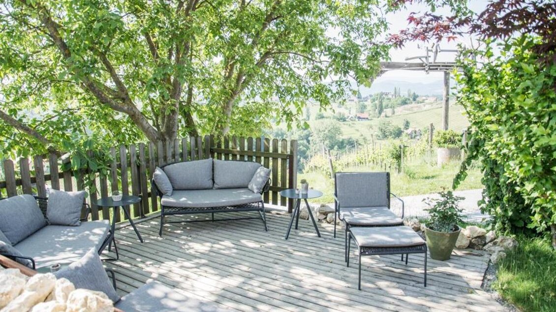 Ein einladender Außenbereich mit modernen Gartenmöbeln und viel grüner Vegetation. Die sonnige Terrasse bietet einen Blick auf die umliegende Landschaft. | © Magdalena Koinegg