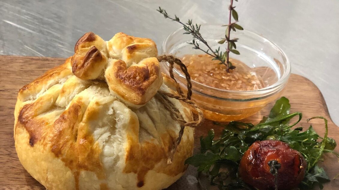 Ein gebackenes Gericht in Teig, schön dekoriert mit Kräutern. Dazu gibt es eine Schale mit Sauce und eine kleine Tomate. | © Landhotel am Gut Moser | Familie Kapun