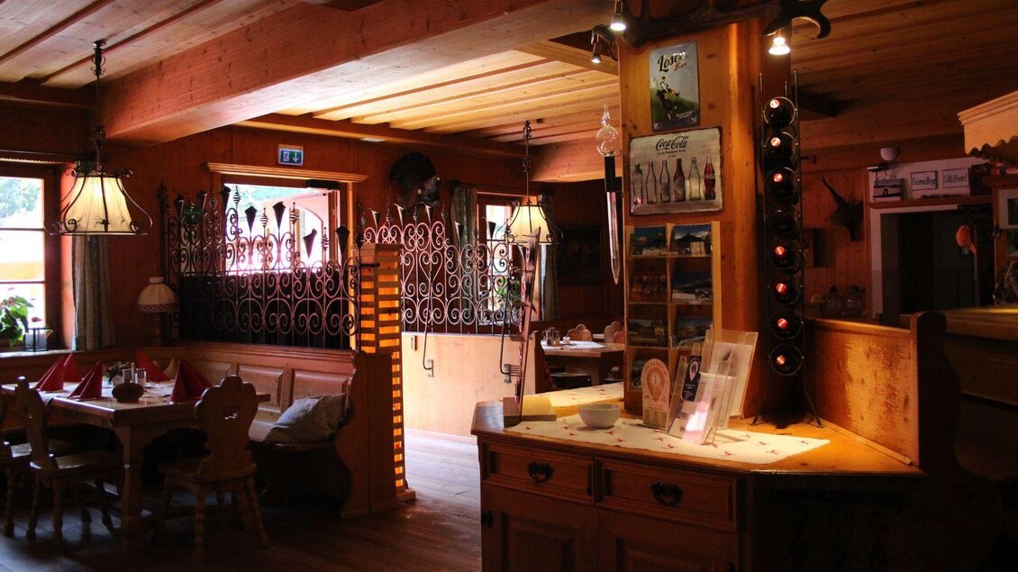 Ein gemütliches Restaurant mit Holzdekor und warmem Licht. Tische sind eingedeckt, und an der Wand sind verschiedene Dekorationsstücke zu sehen. | © Viola Lechner