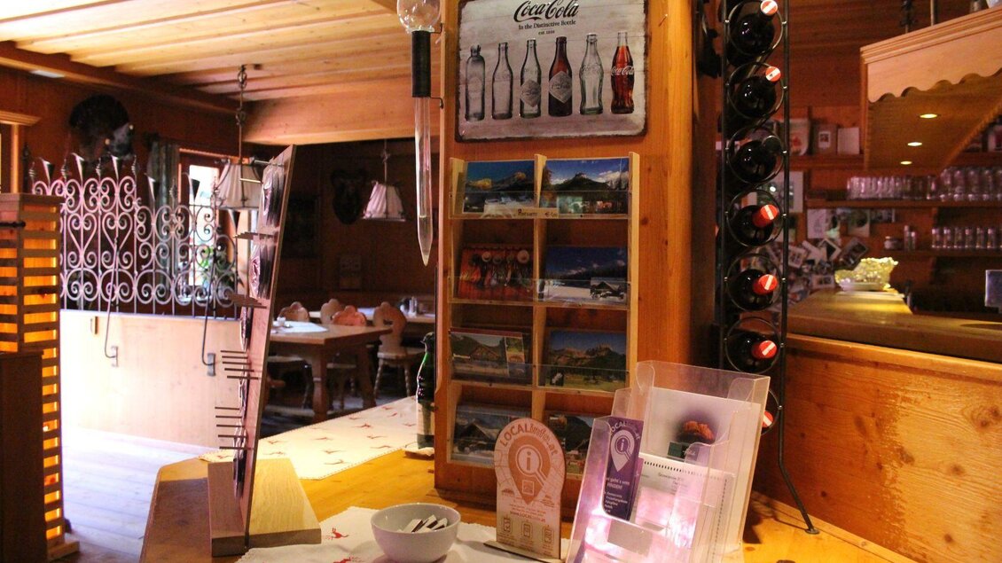 Ein gemütliches Restaurant mit Holzinterieur. An der Wand hängen Flaschen und Bilder, während der Tisch gut dekoriert ist. | © Viola Lechner