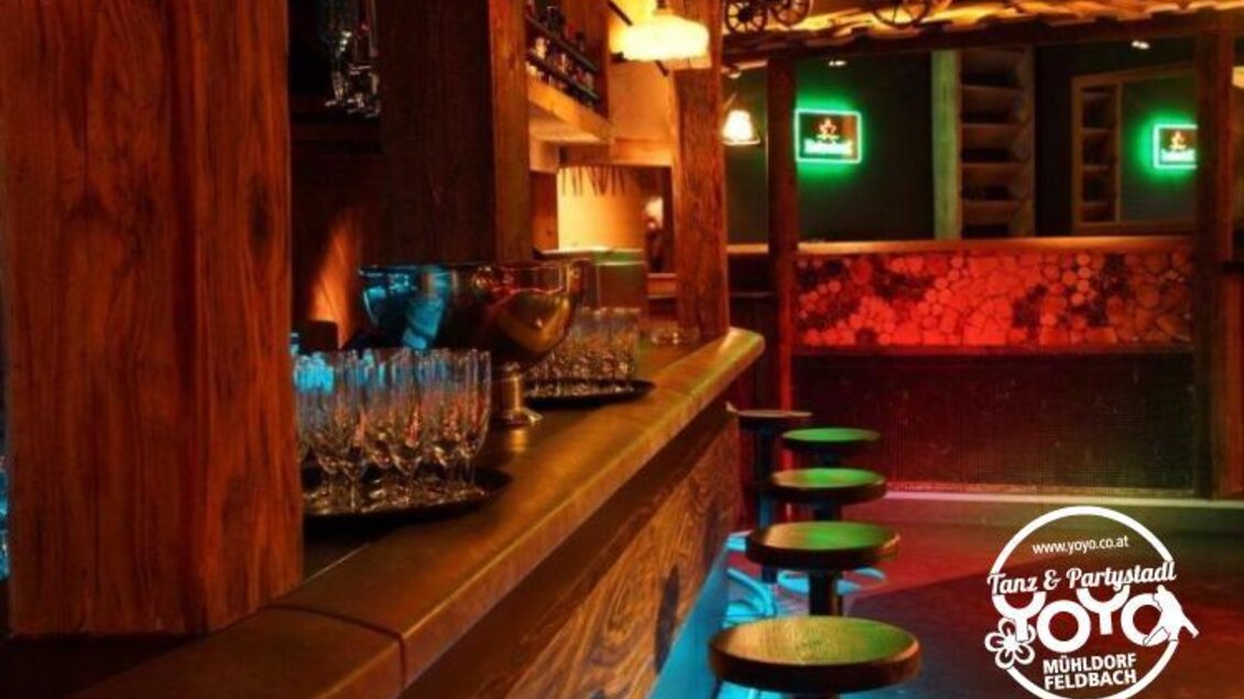 Eine gemütliche Bar mit Holzverkleidung und stilvollen Leuchten. Stühle und Gläser sind bereit für die Gäste. | © Yoyo Feldbach