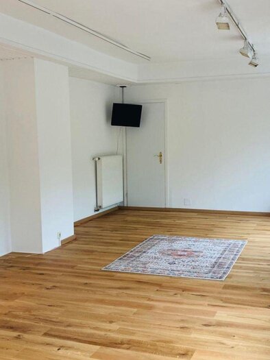 Ein helles, gemütliches Zimmer mit Holzfußboden und großen Fenstern. Es gibt eine kleine Pflanze und eine dekorative Sitzecke. | © Kathrin Leitner