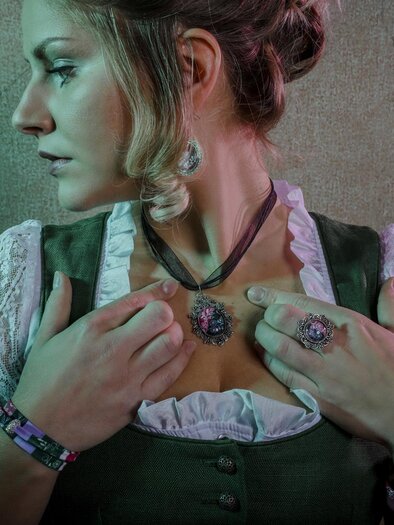 Eine Frau trägt ein traditionelles Outfit mit filigranem Schmuck. Sie posiert seitlich und blickt nachdenklich in die Ferne. | © Fotowerkstatt Irdning, Stefanie Pulsinger