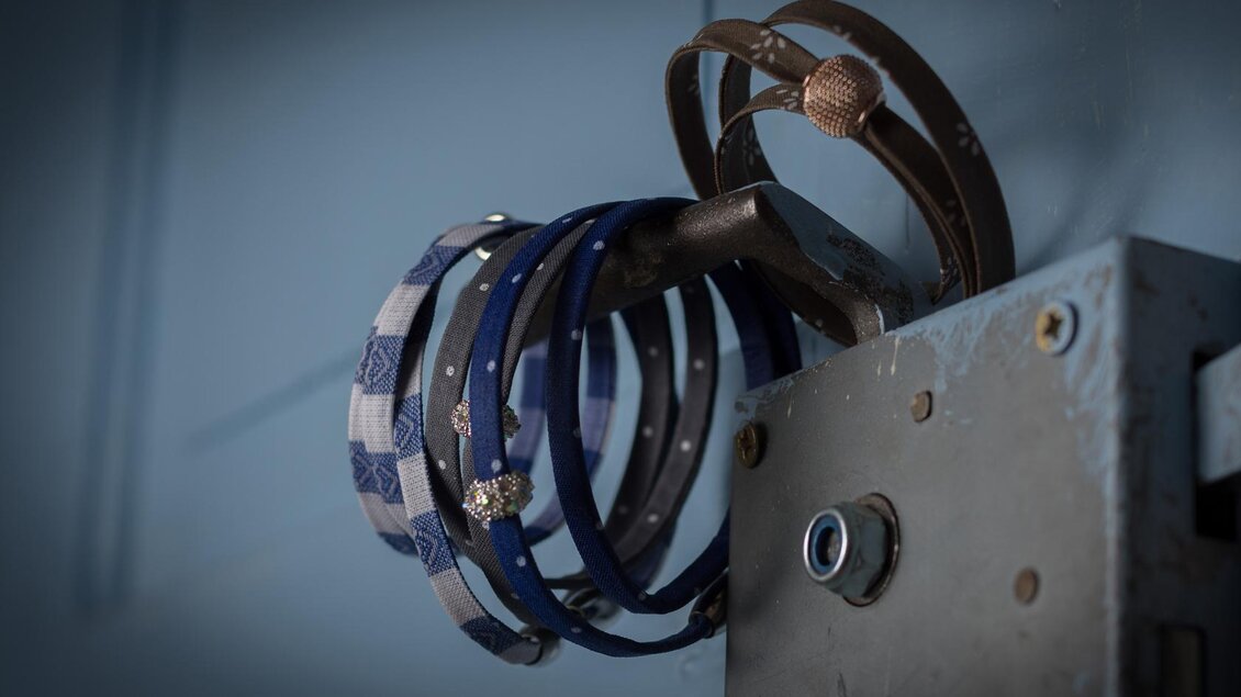 Ein Türhakenschneider mit mehreren Armbändern in Blau- und Weißtönen. Die Bänder hängen ordentlich und sind leicht sichtbar. | © Christina Neuper