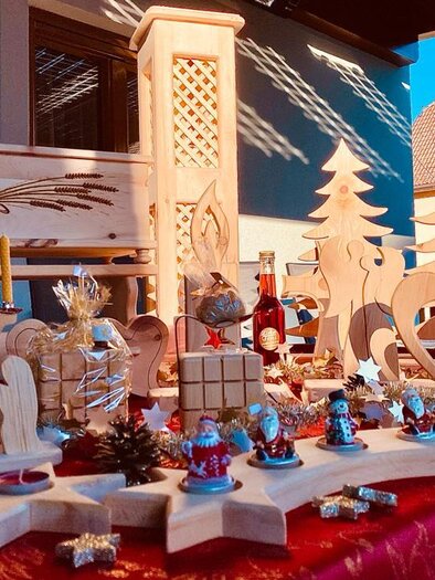 A decorative wooden display with various handcrafted figures, including angels, Christmas trees, and hearts. The scene is festive and showcases artisanal artworks.