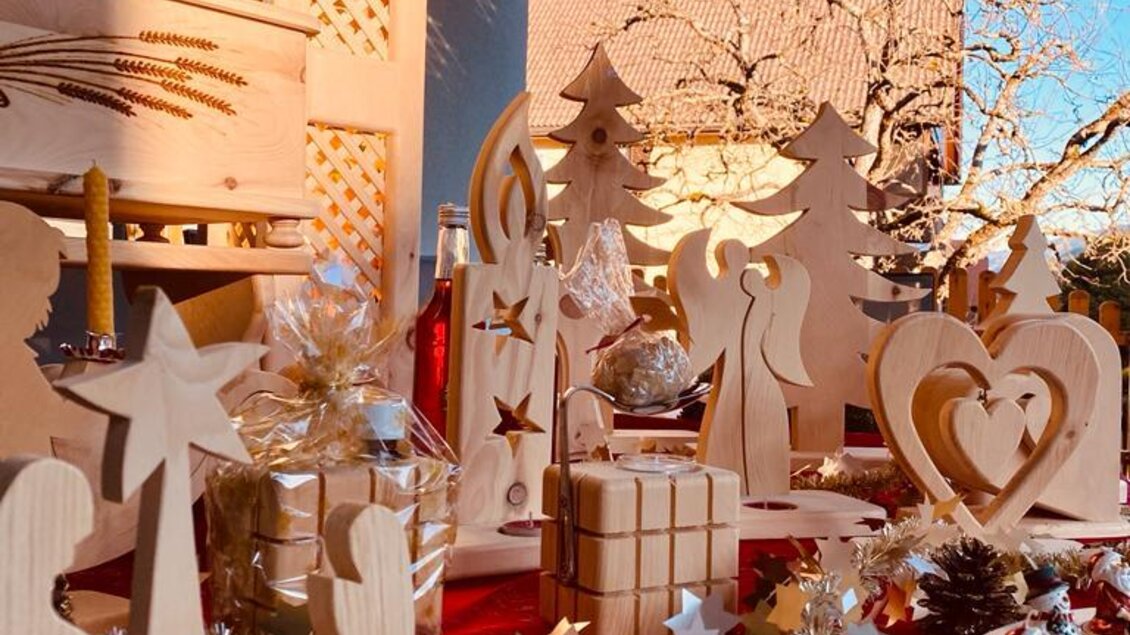 Eine festliche Weihnachtsdekoration mit handgefertigten Holzfiguren. Im Hintergrund ist ein klarer blauer Himmel zu sehen.