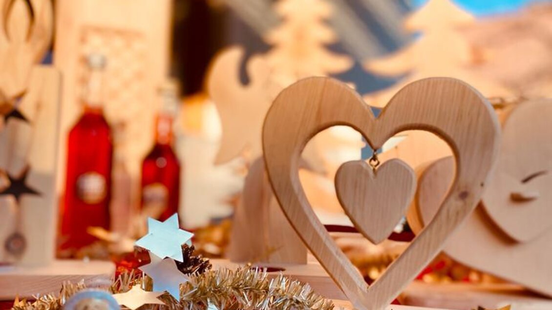 Ein festlich dekorierter Tisch mit Holzfiguren und Weihnachtsmotiven. Im Vordergrund steht eine kleine Santa-Figur und Sterne aus Papier.