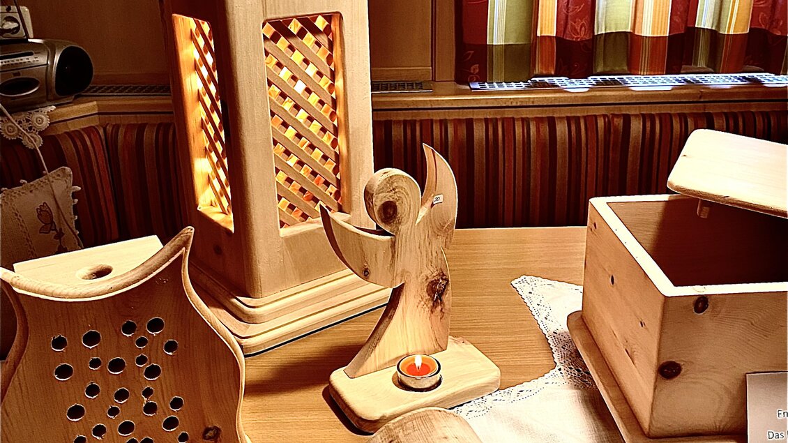 Holzkunsthandwerk mit verschiedenen dekorativen Objekten auf einem Tisch. Die Stücke zeigen kreative Formen und Designs, darunter eine Laterne und eine Box. | © Zirben Toni