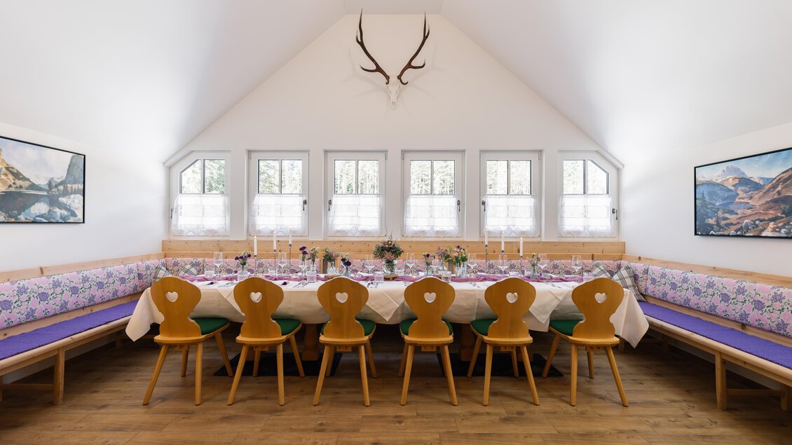 Ein eleganter Essraum mit einer langen Tafel, umgeben von Holzstühlen. Die Wände sind mit Bildern dekoriert, und Geweihe hängen an der Decke. | © Zloam Wirt, www.zloamwirt.at