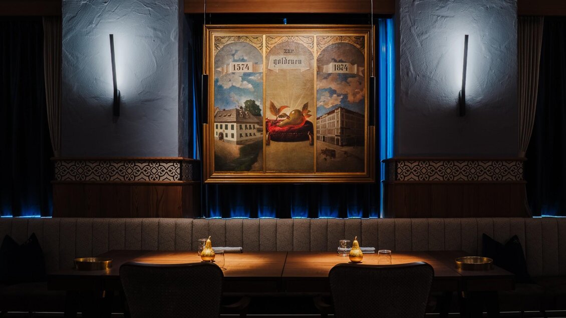 Wandgemälde mit historischen Motiven über Sitzbank im stilvoll beleuchteten Restaurant | © Zur goldenen Birn