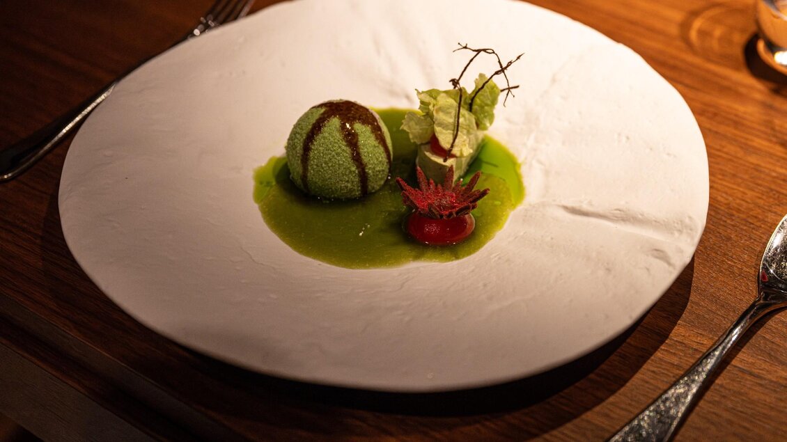 Dessertkugel auf grüner Sauce mit dekorativen Elementen auf weißem Teller | © 5komma5sinne - Rene Strasser Fotografie