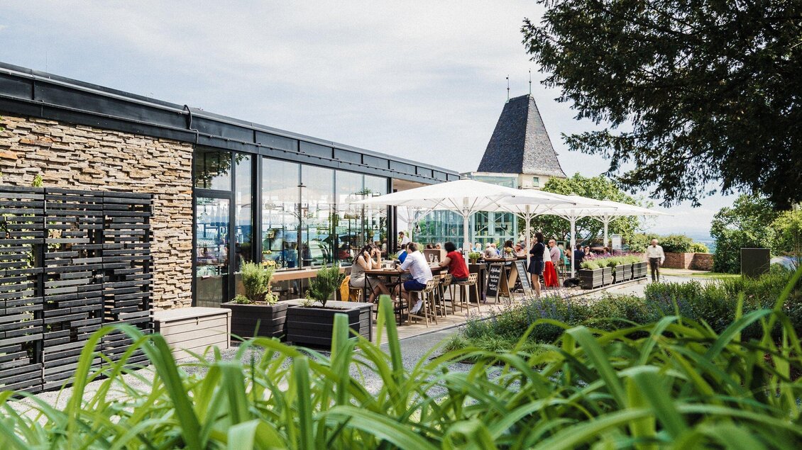 Ein modernes Restaurant mit gemütlicher Terrasse. Gäste genießen die Atmosphäre im Freien unter einem Sonnenschirm. | © aiola