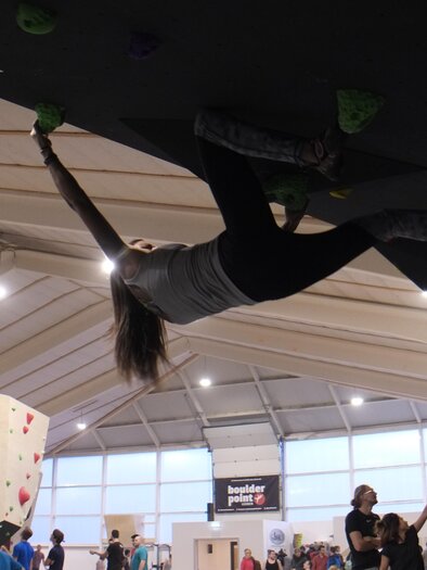A climbing gym with several people bouldering. A climber is seen hanging on the wall in action. | © boulderpoint Leoben