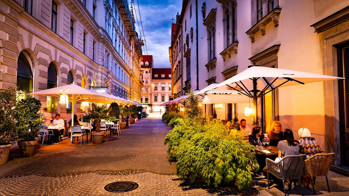 Eine gemütliche Straße mit Restaurants im Freien und Sonnenschirmen. Die Gebäude sind historisch und die Umgebung ist einladend. | © El Gaucho - Werner Krug