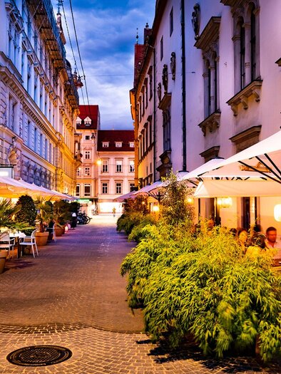 A cozy street with outdoor restaurants and umbrellas. The buildings are historic and the surroundings are inviting. | © El Gaucho - Werner Krug
