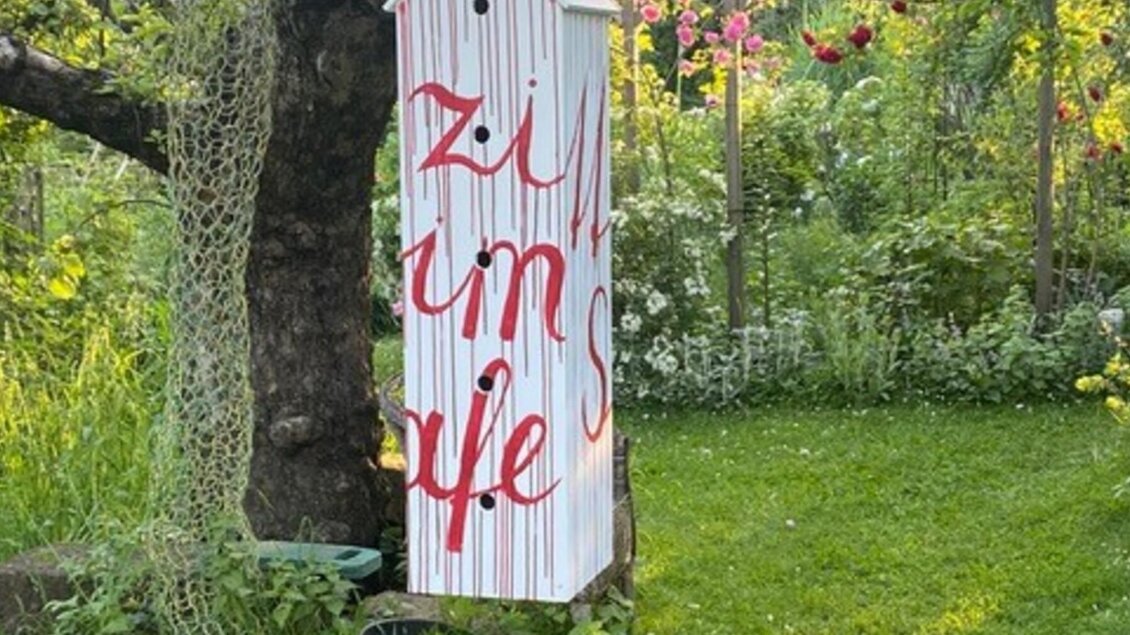 Beschriftetes Kunstobjekt im kunstGarten Graz vor grünem Gartenhintergrund  | © kunstGarten