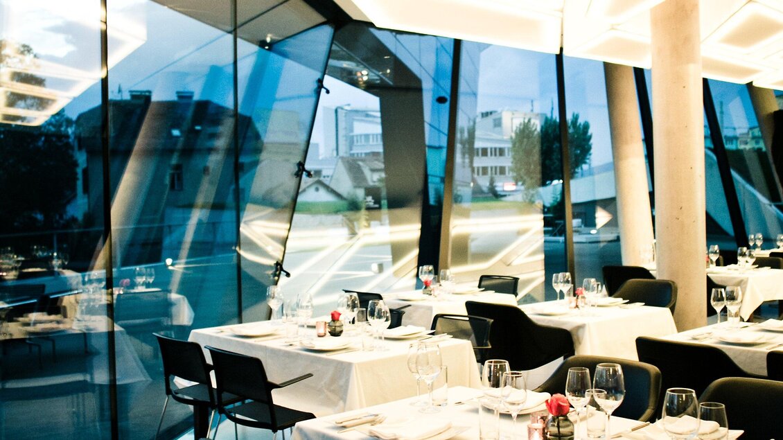Ein modernes Restaurant mit großen Fenstern und eleganten Tischen. Die Atmosphäre ist hell und einladend. | © nullneun
