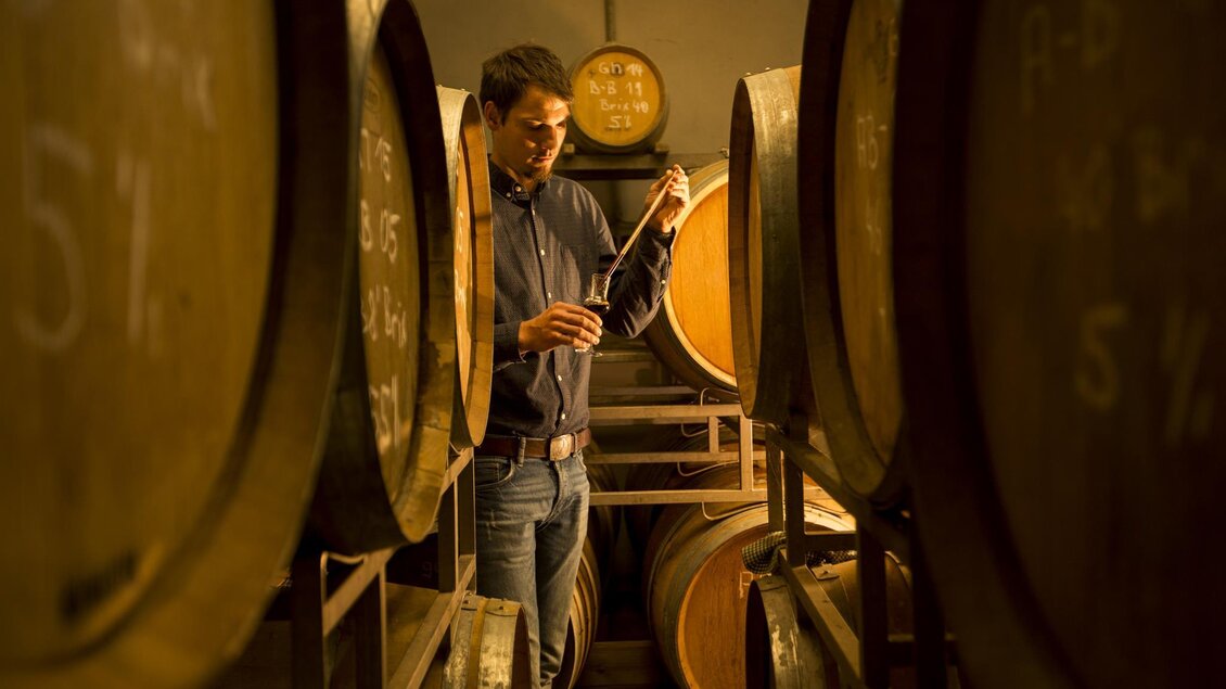 Seppi zwischen den Holzfässern im Keller | © Obsthof Neumeister, Josef Neumeister
