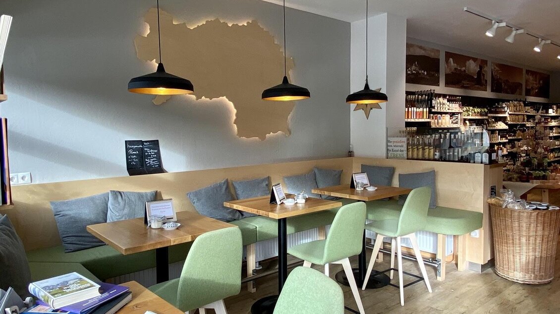 Ein modernes Café mit hellen Wänden und Holzdetails. Die grünen Stühle und warmen Lichtquellen schaffen eine einladende Atmosphäre. | © pur Styria - der Dorfladen