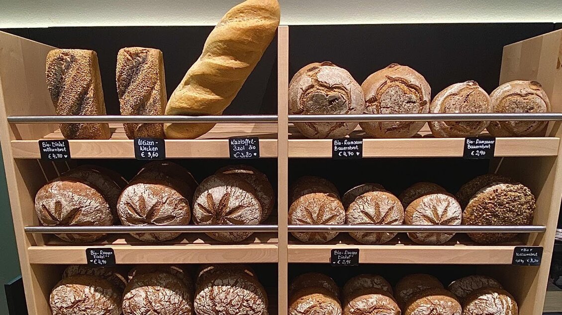 Eine Auswahl an frischem Bio-Brot und Brötchen in einer Bäckerei. Die Auslage zeigt verschiedenste Brotsorten in Körben und Regalen. | © pur Styria - der Dorfladen
