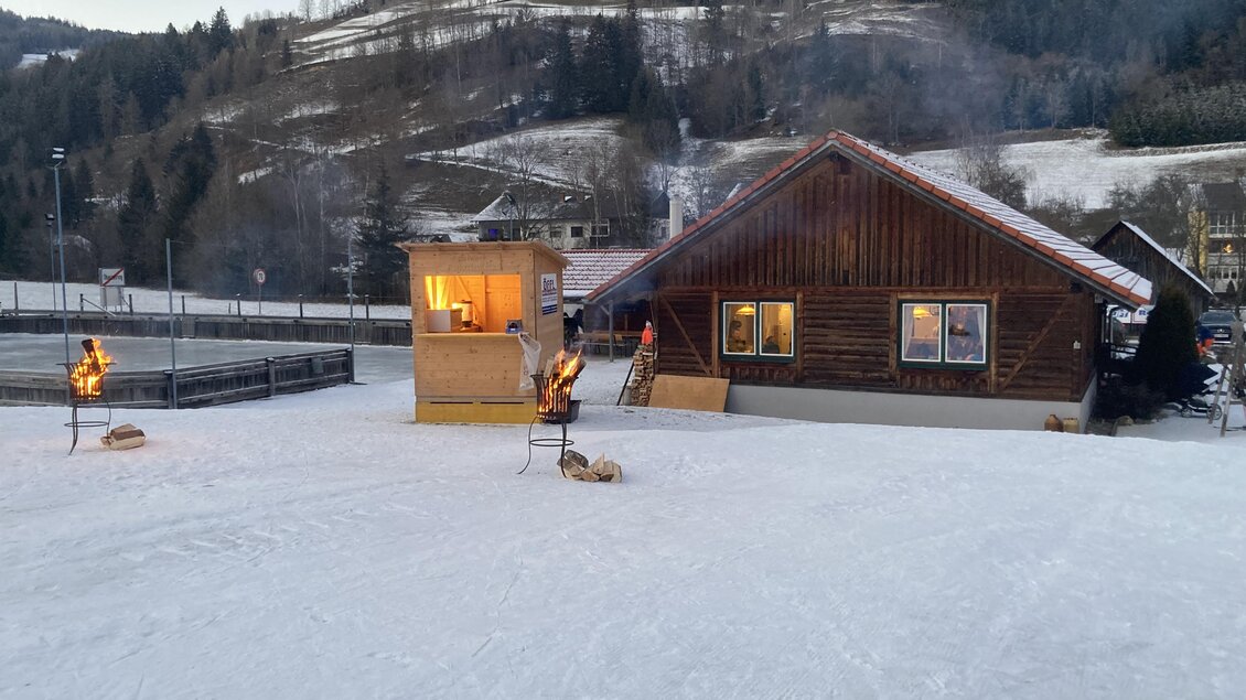 Ein gemütliches Holzhaus in einer verschneiten Landschaft. Im Vordergrund stehen Fackeln und die Umgebung ist von Bäumen und Hügeln umgeben. | © Jürgen Strohmeyer