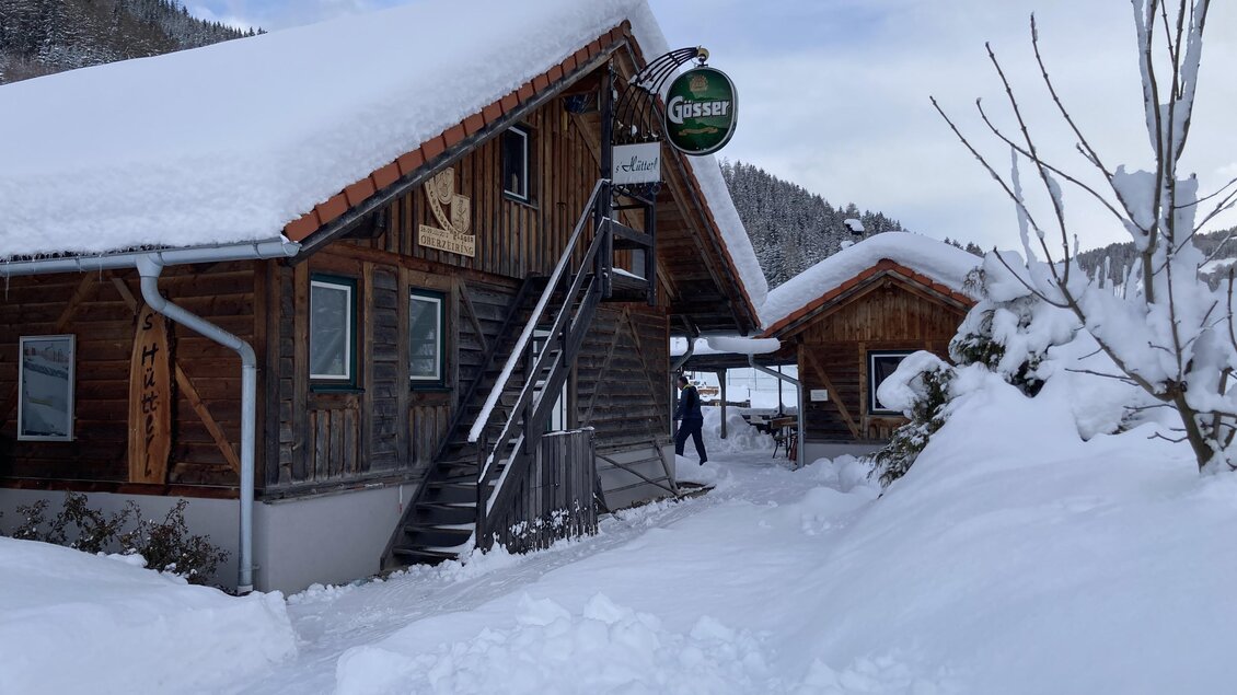 Ein schönes Holzhaus mit einem schneebedeckten Dach. Die Umgebung ist winterlich, mit viel Schnee und Bergen im Hintergrund. | © Jürgen Strohmeyer