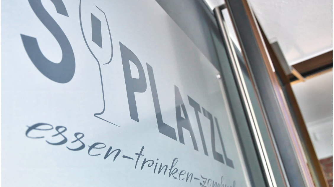 Ein Schriftzug auf einer Glasscheibe zeigt den Namen "SPLATZL". Darunter steht "essen-trinken-zusammen". | © event-fotograf.at