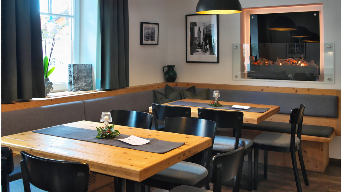 Ein gemütliches Restaurant mit Holztischen und modernen Stühlen. Die Atmosphäre wird durch eine warme Beleuchtung und einen modernen Kamin ergänzt. | © event-fotograf.at