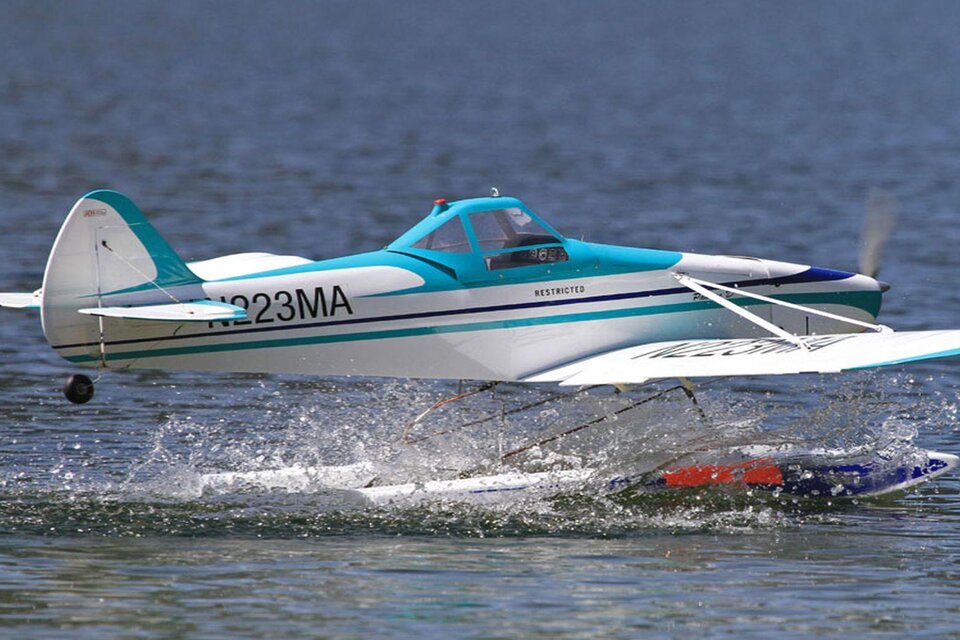 Ein Wasserflugzeug startet von der Oberfläche eines Sees. Es spritzt Wasser und hat eine auffällige blaue und weiße Lackierung. | © Ian Walter