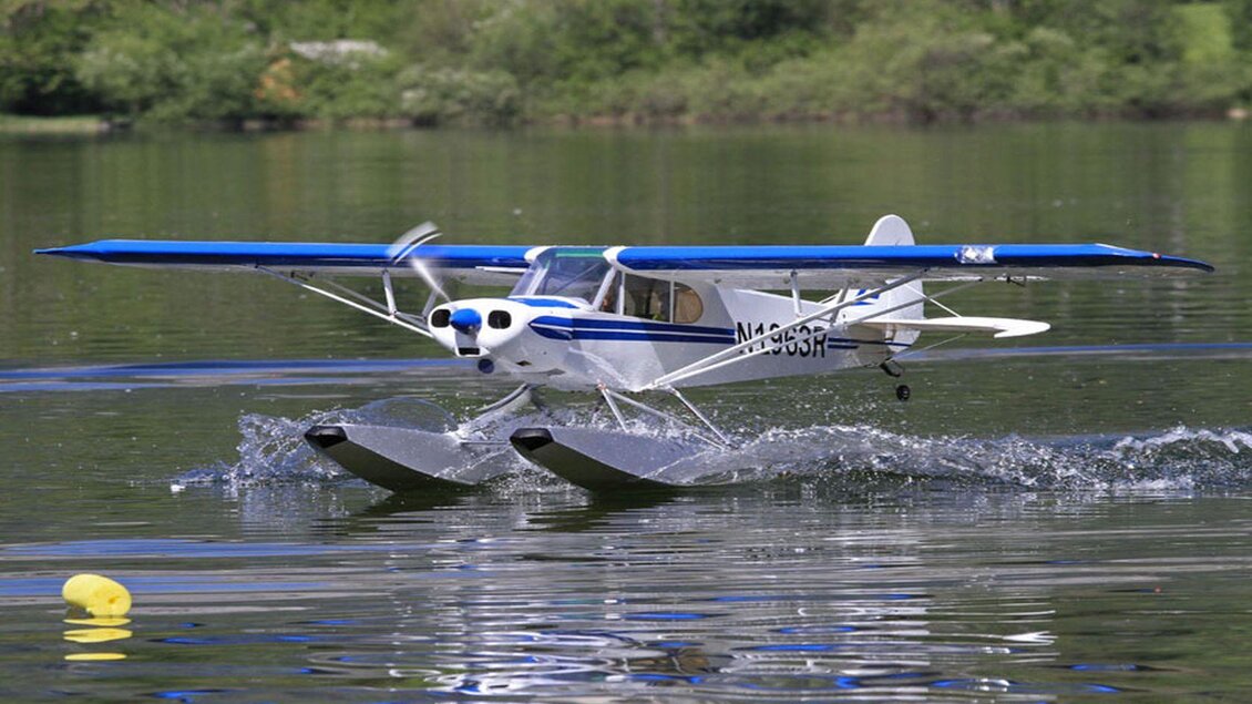 Ein kleines Wasserflugzeug landet sanft auf einem ruhigen See. Die Wellen spritzen auf, während das Flugzeug die Wasseroberfläche berührt. | © Ian Walter