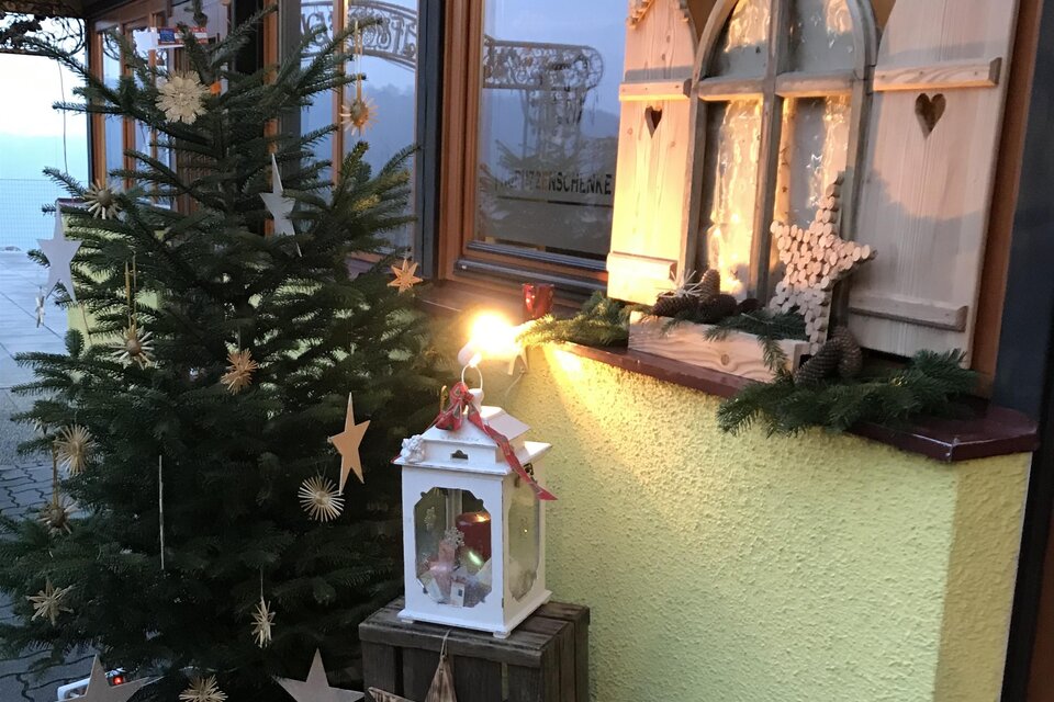 Ein festlich dekorierter Eingangsbereich mit einem Weihnachtsbaum, Sternen und einer Laterne. Die Wände sind mit Weihnachtsdekoration geschmückt. | © Verein "Wir am Berg"
