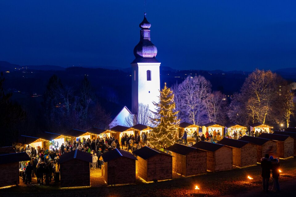 Abendlicher Adventmarkt mit Lichterbaum und Kirche in St. Bartholomä | © Region Graz-Harry Schiffer