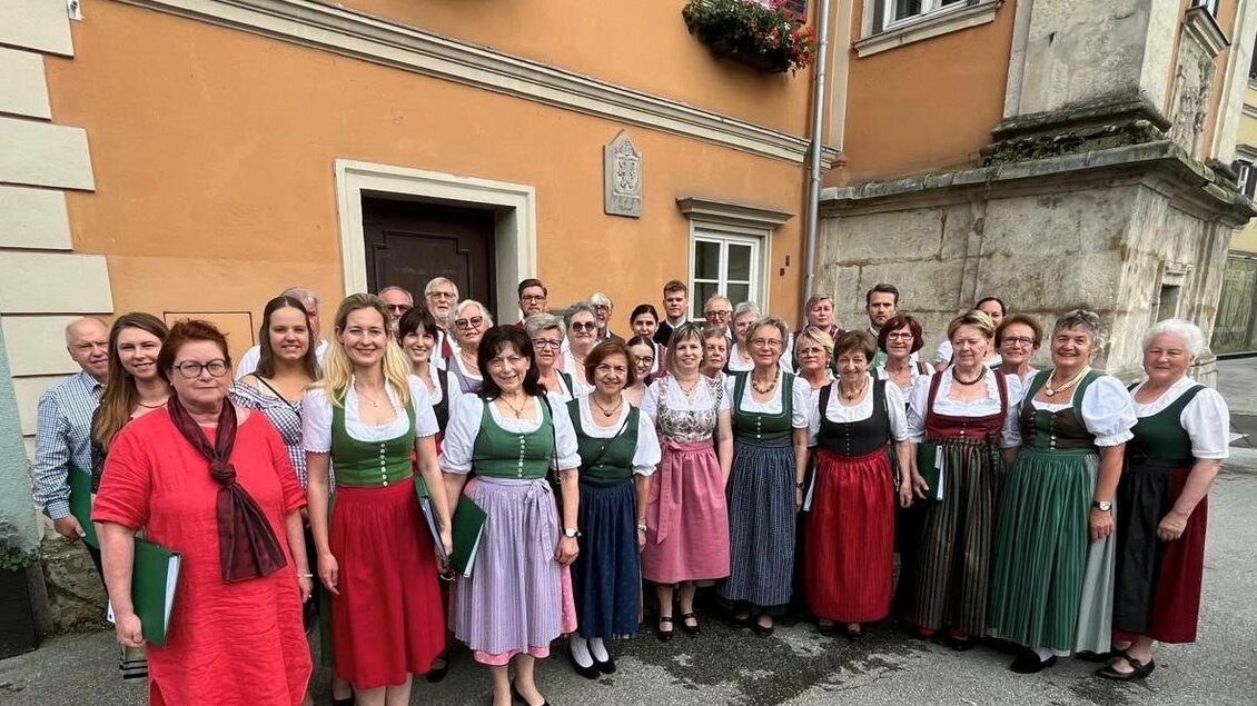 Eine Gruppe von Menschen in traditioneller Tracht steht vor einem Gebäude. Sie lächeln und posieren für das Foto. | © Koiner-Graupp