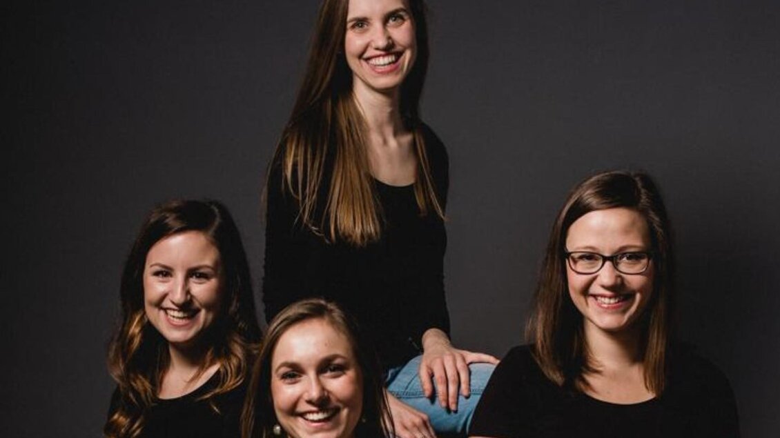 Das Gesangsensemble Puella, mit vier jungen Damen posieren für das Bild. Mit einem schwarzen Hintergrund.   | © Theater & Kultur Premstätten