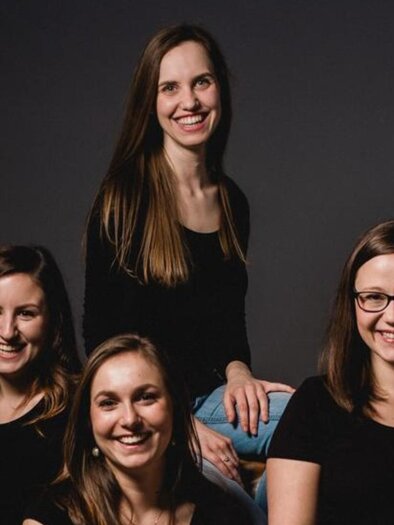 Das Gesangsensemble Puella, mit vier jungen Damen posieren für das Bild. Mit einem schwarzen Hintergrund.   | © Theater & Kultur Premstätten
