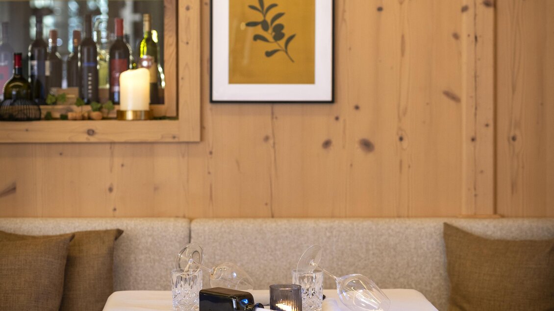 Ein gemütliches Restaurant mit einem Holzinterieur und einem dekorativen Bild an der Wand. Der Tisch ist schön gedeckt und es gibt eine warm glänzende Lampe über dem Tisch. | © Pierer Gastronomie GmbH