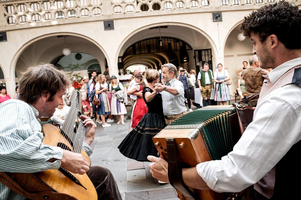 Musikanten mit Gitarre und Harmonika begleiten Paare beim Volkstanz in Graz. | © Ivents Kulturagentur-Ulrike Rauch