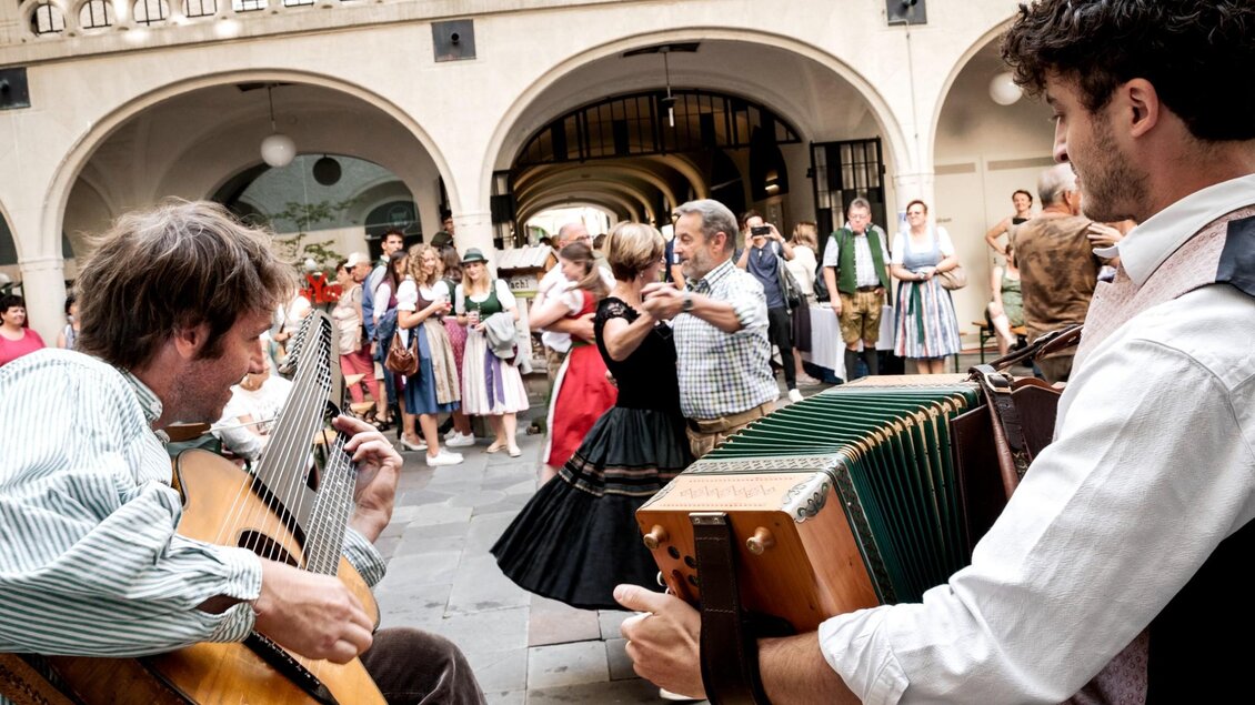 Musikanten mit Gitarre und Harmonika begleiten Paare beim Volkstanz in Graz. | © Ivents Kulturagentur-Ulrike Rauch