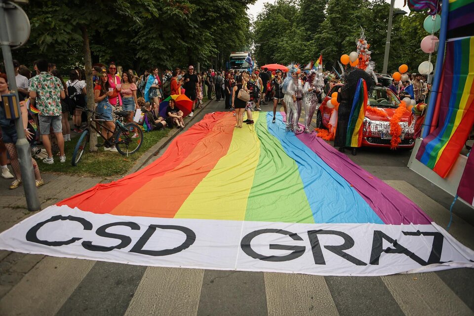 Eine bunte Parade zum Christopher Street Day mit einem großen Regenbogenbanner. Viele Menschen feiern und tragen farbenfrohe Kleidung. | © @Seabstian Neugebauer