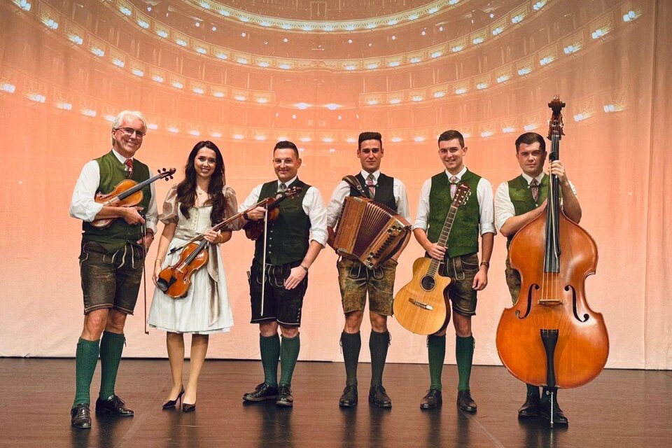 Eine Gruppe von fünf Musikern steht in einem Raum mit musikalischen Noten an der Wand. Sie tragen traditionelle Kleidung und halten Musikinstrumente in den Händen. | © Ausseer Bradlmusi_Bad Aussee_ c Ben Borowskil