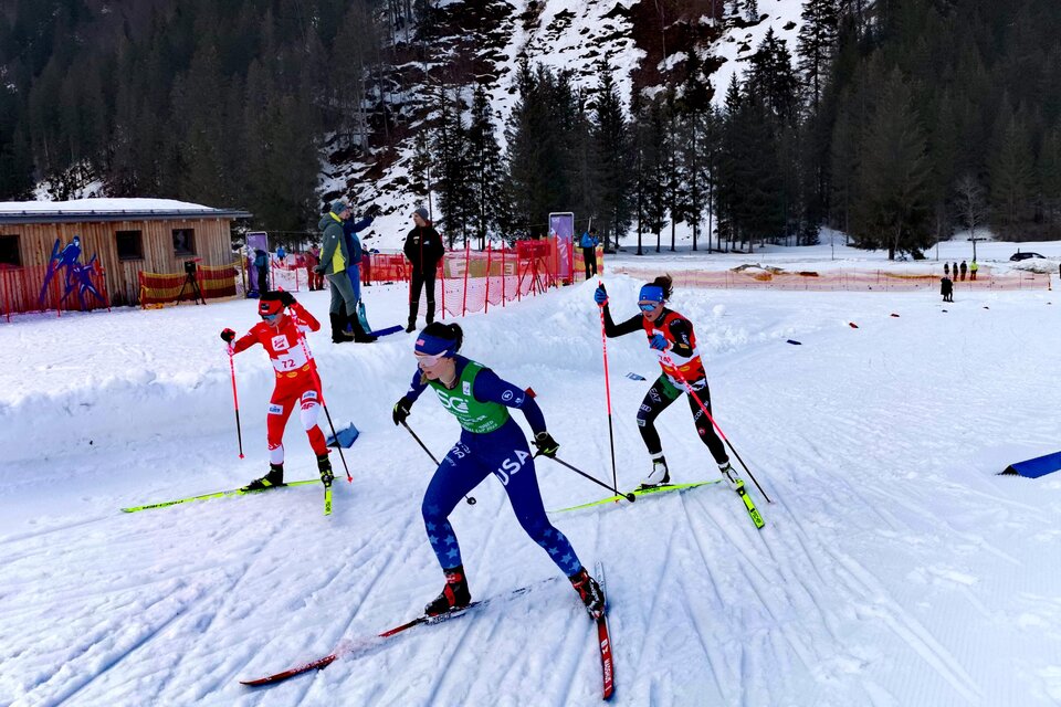 Drei Skilangläufer in einem Wettkampf auf verschneiter Strecke. Im Hintergrund sind Bäume und ein Gebäude zu sehen. | © NAZ Eisenerz