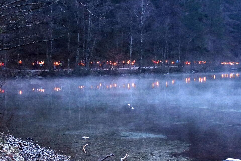 Ein ruhiger See mit sanftem Nebel und schimmernden Lichtern am Ufer. Die Bäume im Hintergrund schaffen eine mystische Atmosphäre. | © Naturfreunde Eisenerz