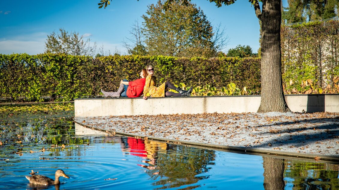 Zwei Frauen sitzen entspannt am Seerosenteich im Skulpturenpark Premstätten. | © Region Graz-Mias Photoart