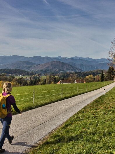 Frau wandert auf Asphaltweg mit Blick auf Hügel und Dörfer bei Gratwein. | © WEGES
